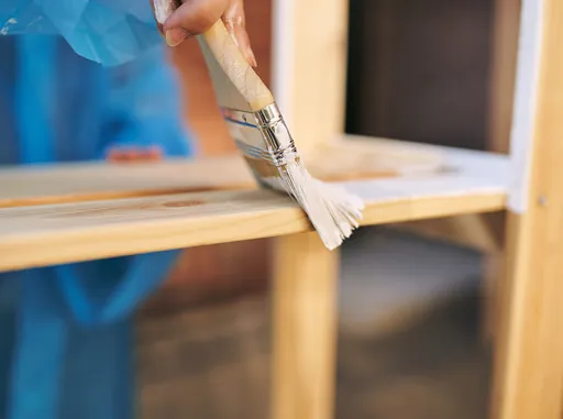 Brush applying finish to a light wood cabinet frame